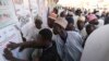 Party agents look at a poster with polling station information in Kano, Nigeria, on Feb. 25, 2023, during Nigeria's presidential and general election. 