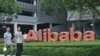 Cette photo d'archive prise le 27 mai 2022 montre des membres du personnel passant devant le logo du géant chinois du commerce électronique Alibaba à son siège social à Hangzhou, dans la province orientale du Zhejiang, en Chine.