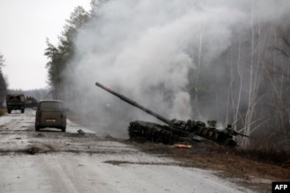 Ruski tenk koji su uništile ukrajinske snage dimi se pored puta u regionu Lugansk, 26. februara, 2022.