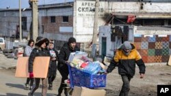 FILE -Wakazi wakiwa wamebeba maji kutoka katika ghala la chakula, katika eneo ambalo linadhibitiwa na serikali ya Jamhuri ya Watu wa Donetsk, nje ya mji wa Mariupol, Ukraine, Ijumaa, March 18, 2022. (AP Photo/Alexei Alexandrov)
