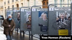 Un homme passe devant des affiches de campagne déchirées près d'un bureau de vote, à Paris, France, le 10 avril 2022. 
