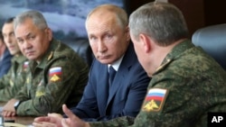 Perezida Vladimir Putin, hagati, Ministri w'Ingabo, Sergei Shoigu, ibumoso, bakurikiranye imyitozo y'igisirikare i Kapustin Yar mu Burusiya 