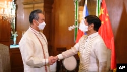 Presiden Filipina Ferdinand Marcos Jr., kanan, menyapa Menteri Luar Negeri China Wang Yi saat ia tiba untuk kunjungan kehormatan di Istana Kepresidenan Malacanang di Manila. (Foto: via AP)
