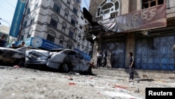 Des habitants de Sanaa marchent près des voitures détruites dans une rue où les combattants Houthis ont récemment affronté les forces loyales à l'ancien président du Yémen Ali Abdallah Saleh, Yémen, le 5 décembre 2017.