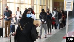 FILE - Travelers wearing masks walk at Jomo Kenyatta International Airport in Nairobi, Aug. 1, 2020. Kenyan officials have raised suspicions over the deaths of 89 Kenyans, most of them domestic workers, in Saudi Arabia.