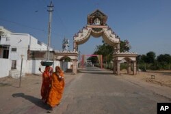Women walks past an entrance gate of Dingucha village in Gandhinagar, India, Nov. 12, 2024.