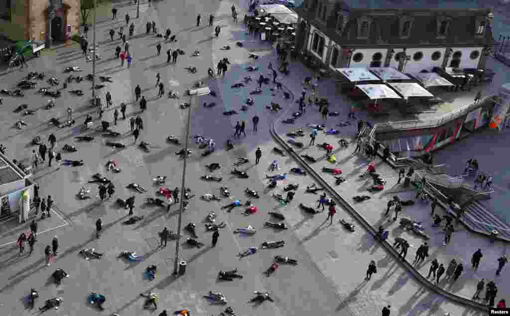 People lay down in a pedestrian zone as part of an art project in remembrance of the 528 victims of the "Katzbach" Nazi concentration camp, in Frankfurt, Germany, Mar. 24, 2014. The inmates of the Katzbach concentration camp, a part of the former Adler industrial factory, were forced into a death march to the concentration camps of Buchenwald and Dachau on Mar. 24, 1945. Some 528 victims of Katzbach are buried at Frankfurt's central cemetery.