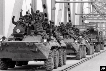 Hình minh họa - Máy bay trực thăng của Hoa Kỳ rời đi, trong khi chiến binh Taliban ngồi trên chiếc xe tăng bị bỏ hoang, bao quanh bởi những bông hoa anh túc đỏ.