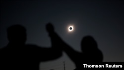 People react while observing a solar eclipse at Incahuasi, a mountain in Chile, July 2, 2019. 