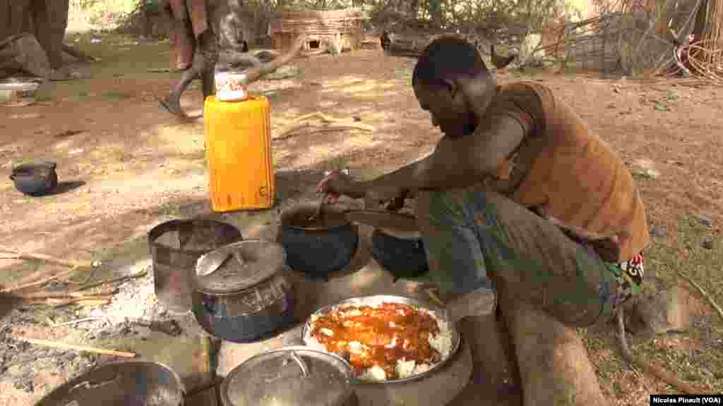 Un jeune pêcheur nigérian en train de préparer son repas dans le village de Tagal, Tchad, le 24 avril 2017 (VOA/Nicolas Pinault)