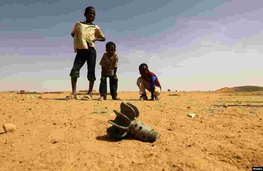 Children look at the fin of a mortar projectile that was found at the Al-Abassi camp for internally displaced persons, after an attack by rebels, in Mellit town, North Darfur, Sudan.