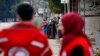FILE - Members of the Syrian Red Cross stand near aid vehicles loaded with food and other supplies that entered the besieged town of Madaya about 15 miles (24 kilometers) northwest of Damascus, Syria, Jan. 11, 2016.