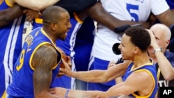 Photo d'archives: Stephen Curry, à droite, et Andre Iguodala Golden State Warriors célébrant leur victoire à l’issue du match 6 comptant pour la finale de la NBA à Cleveland, mardi 16 juin 2015.
