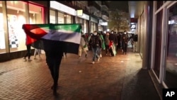 Dalam gambar yang diambil dari video ini, pendukung pro-Palestina berbaris dengan bendera Palestina di dekat stadion Ajax di Amsterdam, Belanda, 7 November 2024. (Foto: AP Photo Intervision)