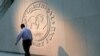 Seorang pria berjalan melewati logo Dana Moneter Internasional (IMF) di kantor pusatnya di Washington, AS, 10 Mei 2018. (Foto: REUTERS/Yuri Gripas)