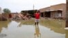 FILE - A man gestures as he wades through a flooded road in the town of Salmaniya, about 35 km southwest of the capital, Khartoum, Sudan, Sept. 17, 2020.